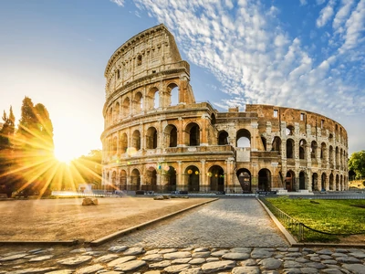 Vue du Colisée de Rome sous un ciel bleu ensoleillé, offrant un panorama emblématique et lumineux de cet ancien chef-d'œuvre architectural