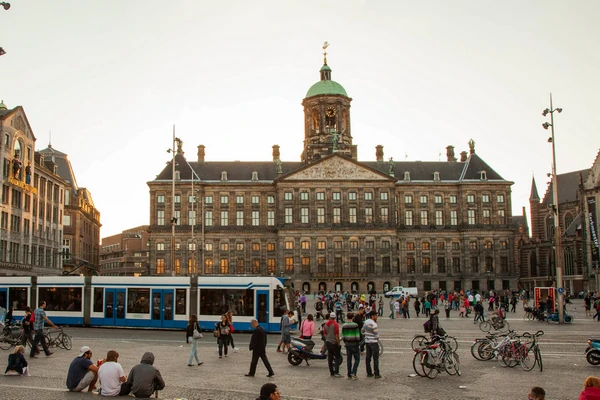 La place centrale avec le Palais Royal et le Monument national, un lieu emblématique de la vie urbaine à Amsterdam.